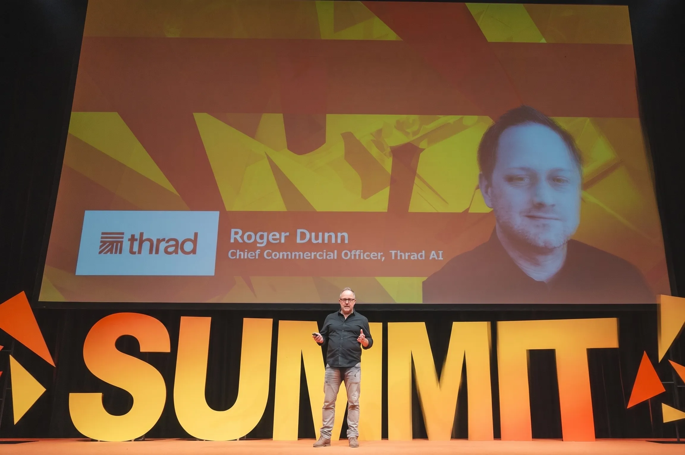 Roger Dunn on stage in front of the Summit letters